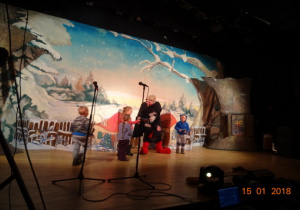 Scenografia - chatka krasnoludków, na scenie 4 dzieci i aktor.